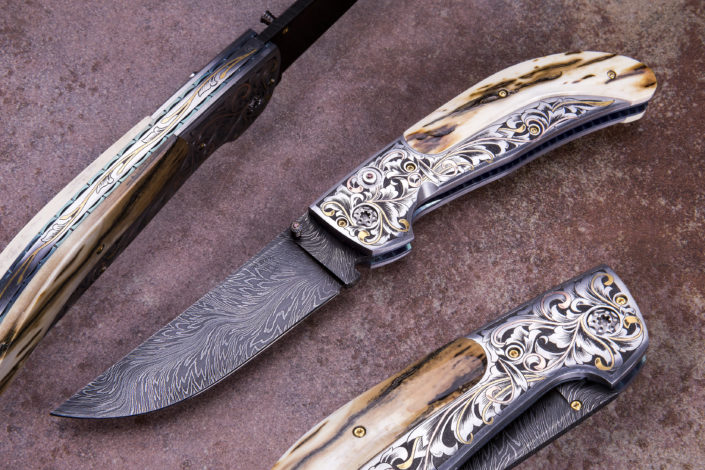 SOLD - The Vaquero, Double Action Automatic, fitted with a 3 3/4" River of Fire Damascus blade forged by Bill Burke, 416 SS bolsters engraved by Alice Carter, and Presentation grade mammoth ivory scales. The "Compadre". This prototype Linerlock folder is fitted with a 3" Doug Ponzio, Turkish Twist Damascus blade, nitre blued Robert Eggerling Mosiac Damascus Bolsters, beautifully engraved by Alice Carter, with inlaid copper and 24k gold. The Mother of Pearl scales are also engraved by Alice Carter. Price $5950.00. Click on image for a hi resolution view.